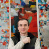A man stands in front of an abstract painting.